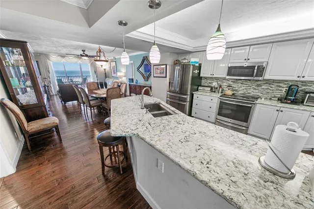 a kitchen with stainless steel appliances kitchen island granite countertop a table chairs stove and refrigerator
