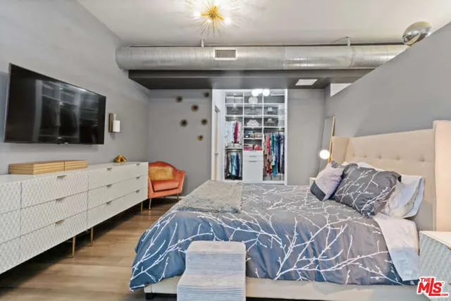a bedroom with a large bed and a flat tv screen on dresser
