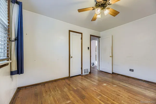 a view of empty room with wooden floor and fan
