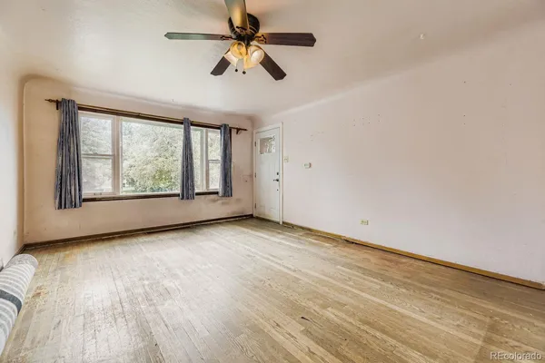 an empty room with wooden floor fan and windows