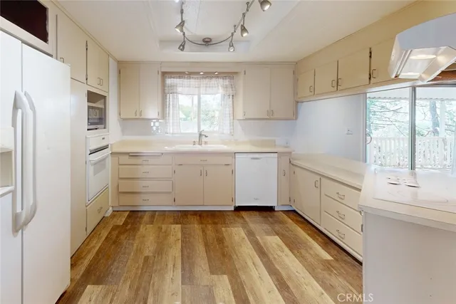 a kitchen with a refrigerator a sink and dishwasher with white cabinets