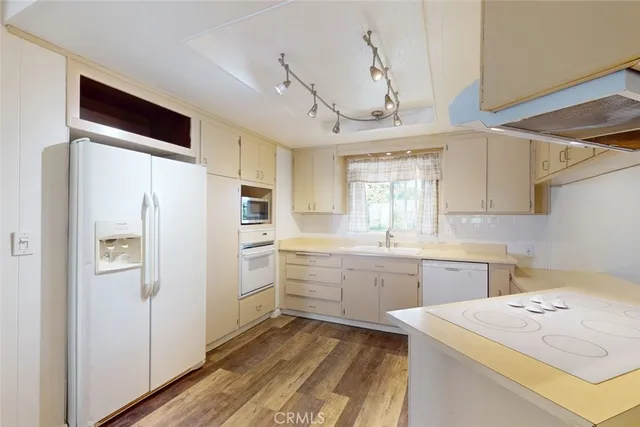 a hall with kitchen island white cabinets and stainless steel appliances