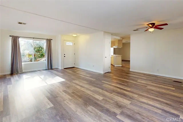 an empty room with wooden floor and windows