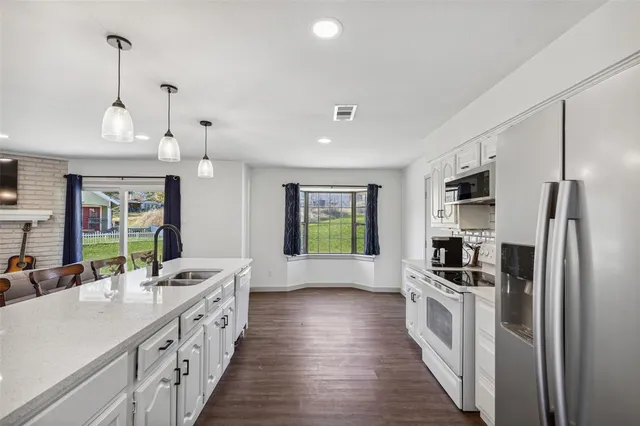 a kitchen with stainless steel appliances kitchen island granite countertop a stove a sink and a refrigerator