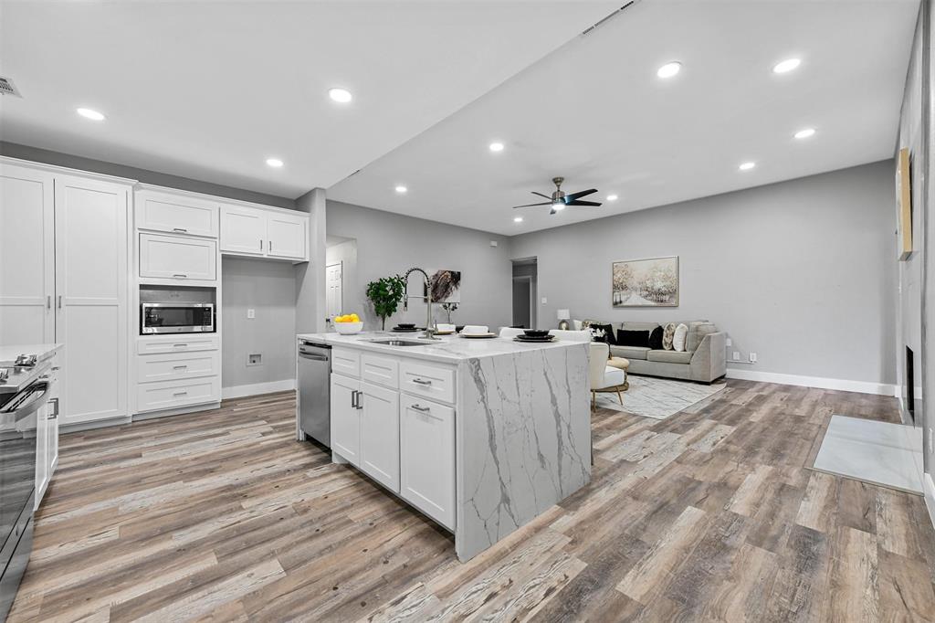 303 Riva Ridge Wylie, TX 75098 - Photo 12 of 38 a large white kitchen with kitchen island a sink a center island and stainless steel appliances