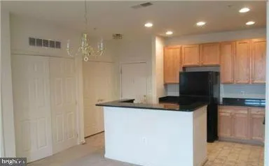 a kitchen with kitchen island granite countertop white cabinets and refrigerator
