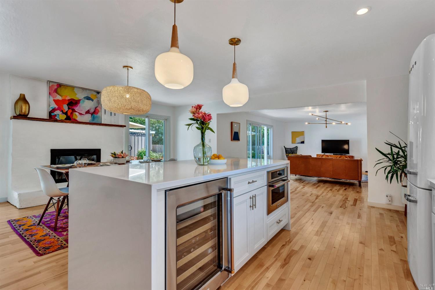 a large white kitchen with a stove a sink dishwasher and a fireplace with wooden floor