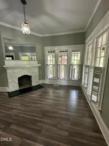 a view of an empty room with wooden floor fireplace and a window