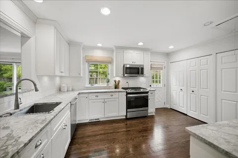 a kitchen with stainless steel appliances granite countertop a sink dishwasher stove and refrigerator with wooden floor