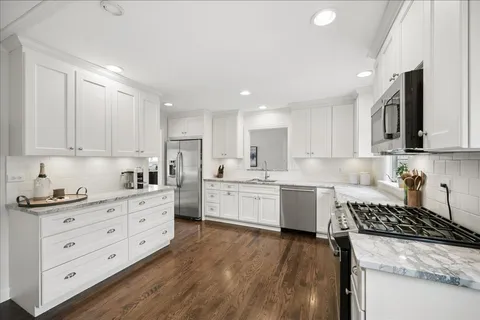 a kitchen with granite countertop a sink a counter space appliances and cabinets