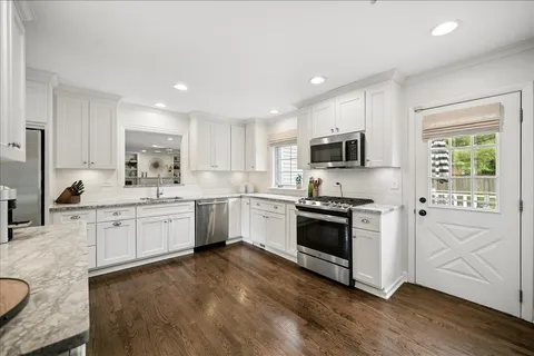 a kitchen with granite countertop white cabinets and stainless steel appliances