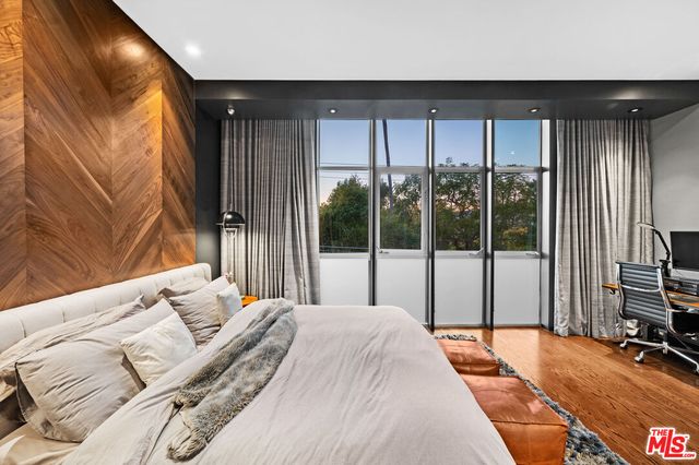 a bedroom with a bed and a flat tv screen next to a large window
