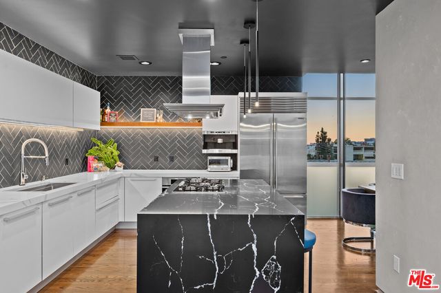 a kitchen with stainless steel appliances granite countertop a sink a stove and a refrigerator