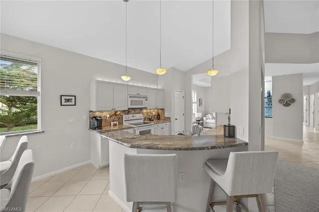 a kitchen with stainless steel appliances granite countertop a sink a stove a dining table and chairs