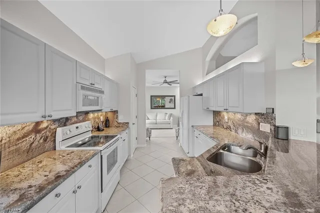 a kitchen with granite countertop a sink a stove and cabinets