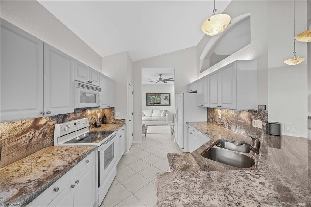 6864 Ascot Drive, Unit 5202 Naples, FL 34113 - Photo 12 of 36 a kitchen with granite countertop a sink a stove and cabinets