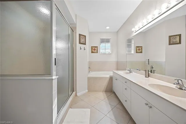 a spacious bathroom with a double vanity sink a mirror and a bathtub