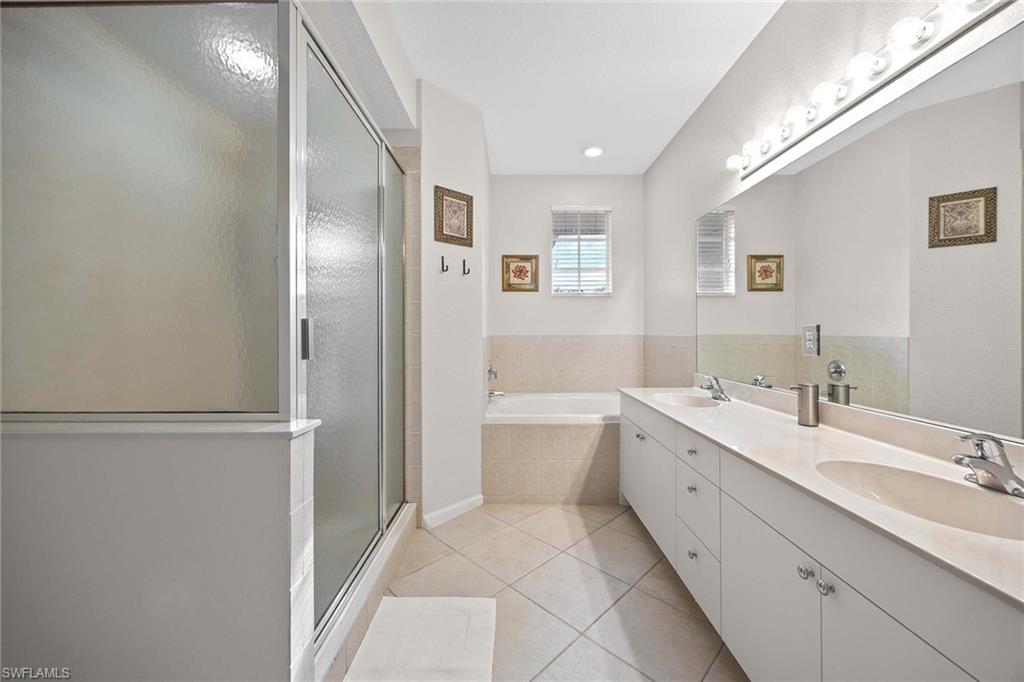 6864 Ascot Drive, Unit 5202 Naples, FL 34113 - Photo 20 of 36 a spacious bathroom with a double vanity sink a mirror and a bathtub