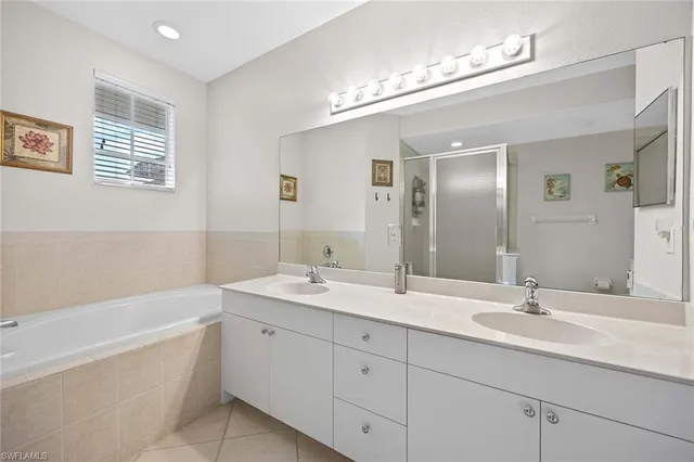a bathroom with a double vanity sink a large mirror and a bathtub