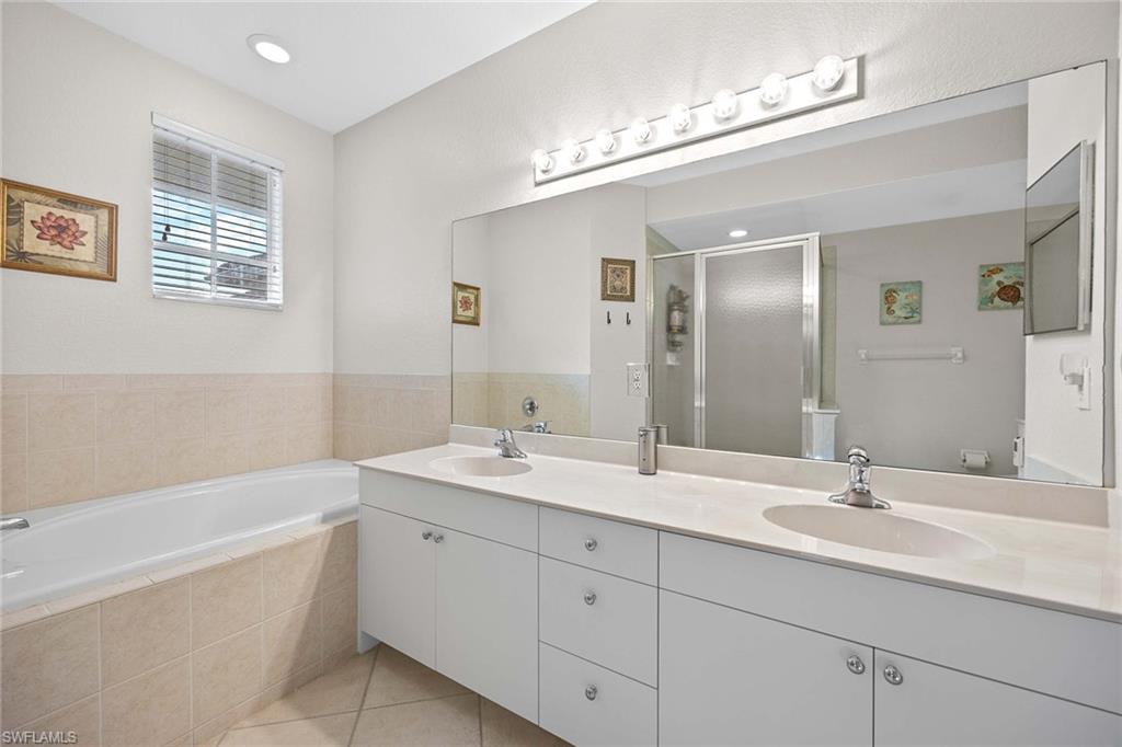 6864 Ascot Drive, Unit 5202 Naples, FL 34113 - Photo 21 of 36 a bathroom with a double vanity sink a large mirror and a bathtub