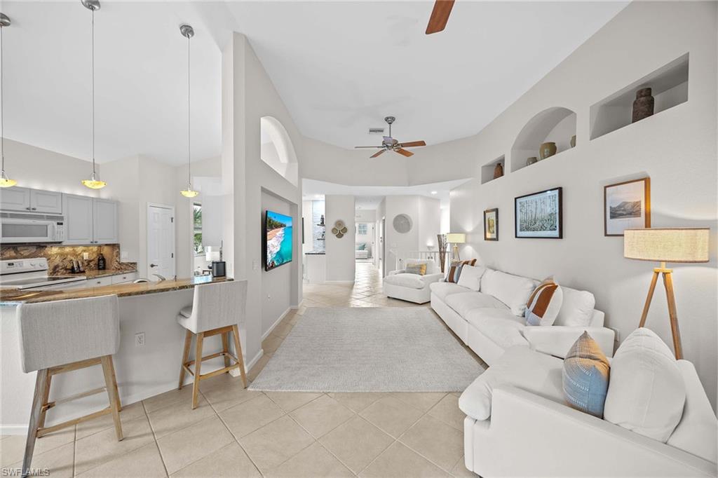 6864 Ascot Drive, Unit 5202 Naples, FL 34113 - Photo 10 of 36 a living room with furniture and a dining table with kitchen view