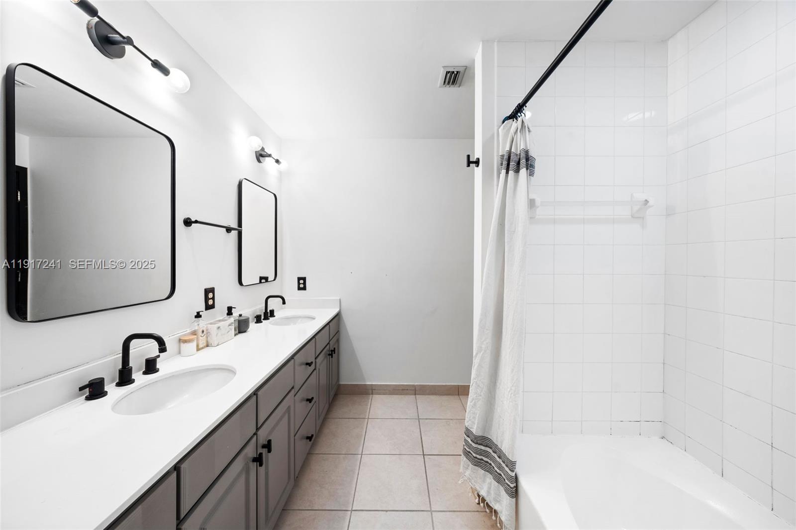 2001 Biscayne Boulevard, Unit 2409 Miami, FL 33137 - Photo 15 of 48 a bathroom with a double vanity sink a mirror and a bathtub