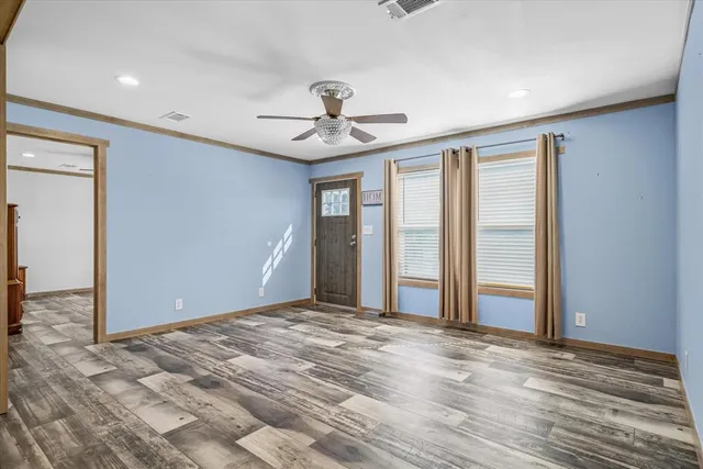 a view of a livingroom with a chandelier fan and wooden floor