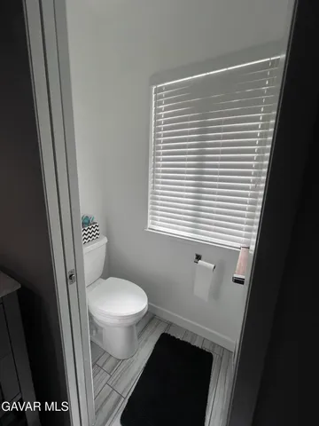 a white toilet sitting in a bathroom next to a window