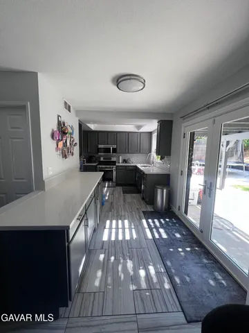 a kitchen with granite countertop a stove a sink dishwasher and a dining table with wooden floor