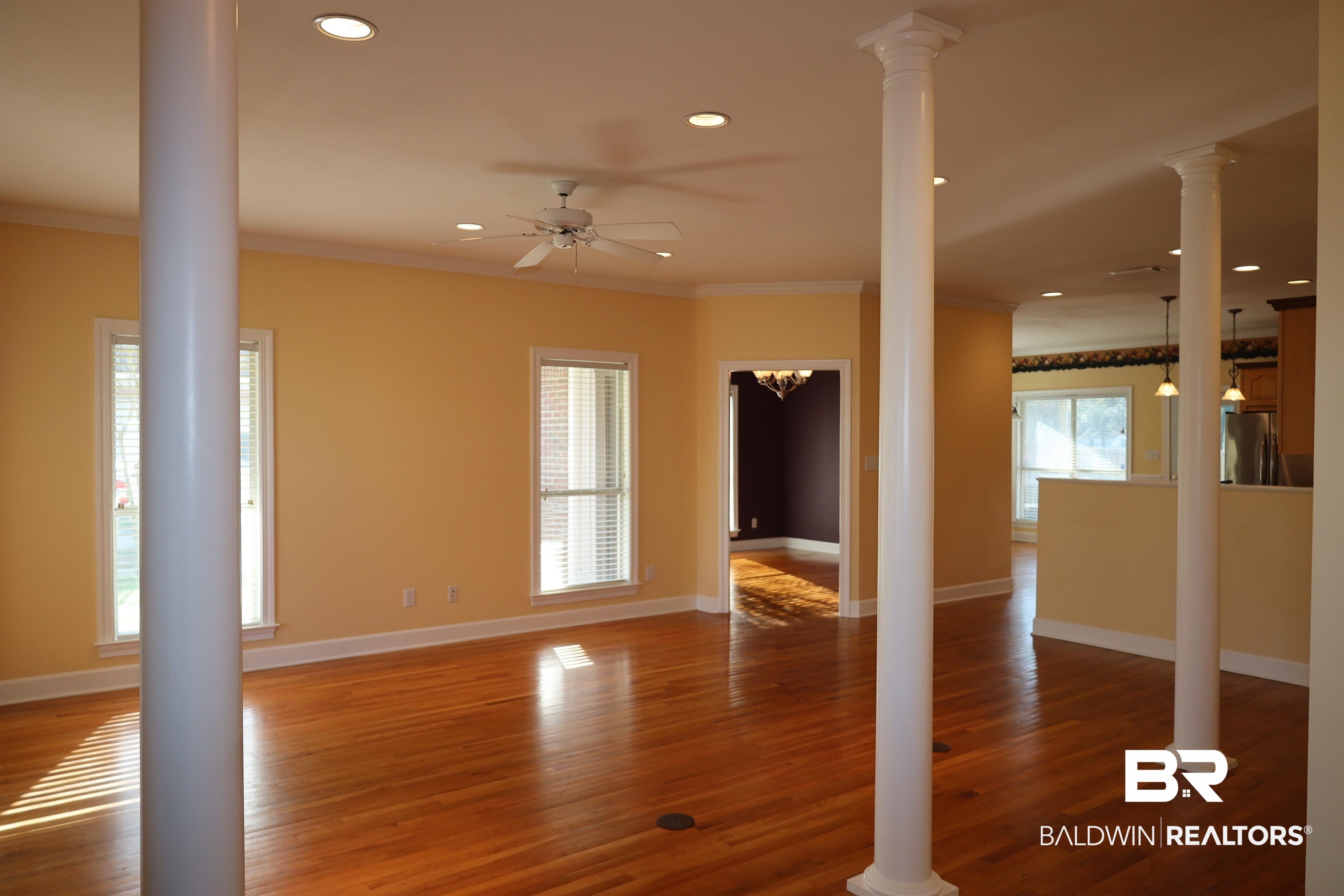 111 Destrehan Road Fairhope, AL 36532 - Photo 6 of 29 Unfurnished living room with decorative columns, baseboards, wood finished floors, and crown molding