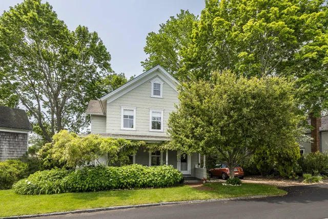 a front view of a house with a yard and potted plants