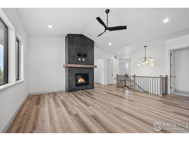 a view of an empty room with wooden floor fireplace and a window