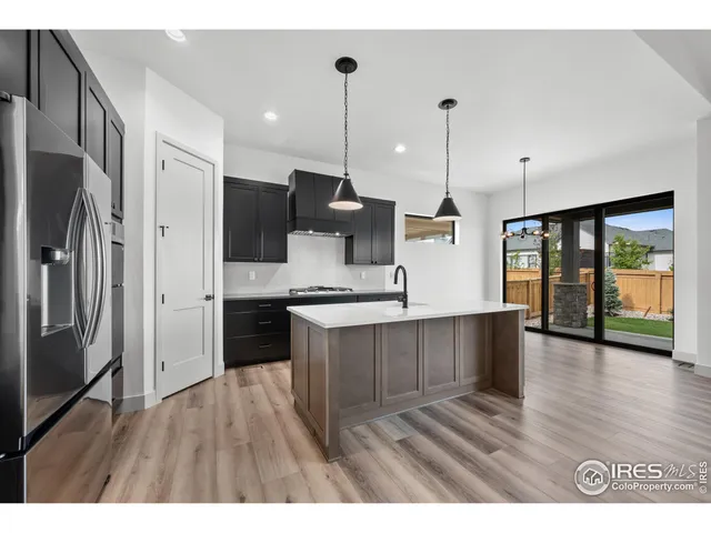 a open kitchen with stainless steel appliances granite countertop a refrigerator a sink dishwasher a oven and a kitchen island with wooden floor