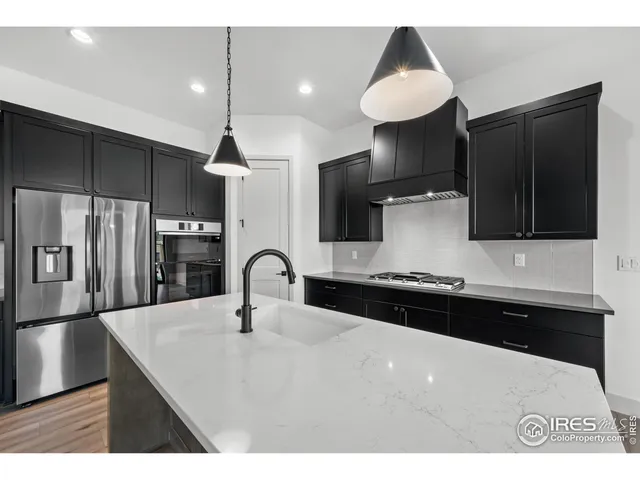 a kitchen with stainless steel appliances a sink a refrigerator and cabinets