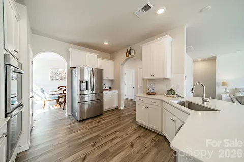 a kitchen with stainless steel appliances a refrigerator a stove top oven a sink dishwasher and a refrigerator with wooden floor
