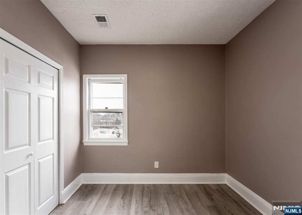 86 Hunter Street Lodi, NJ 07644 - Photo 9 of 18 an empty room with wooden floor and windows