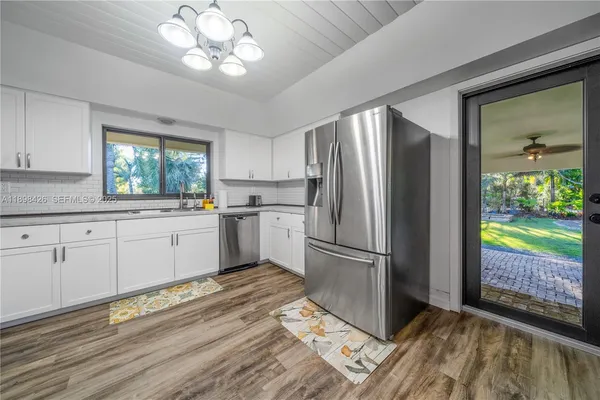 a kitchen with a refrigerator a sink cabinets and wooden floor