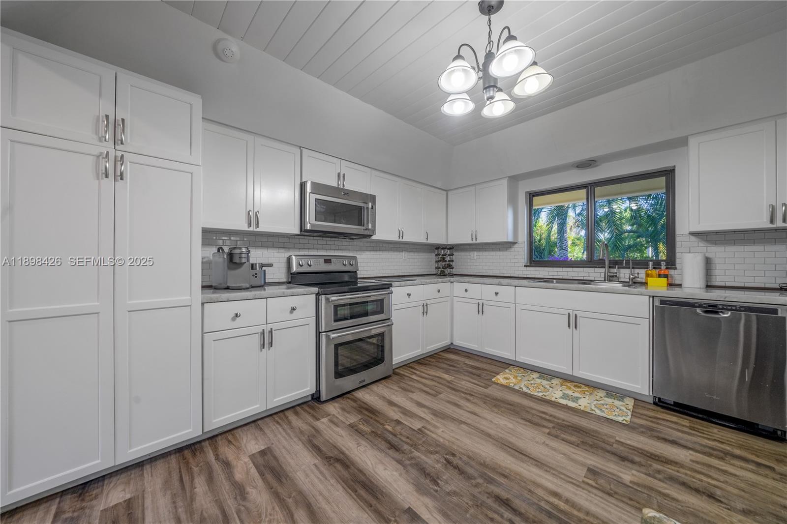 29880 Southwest 183rd Court Homestead, FL 33030 - Photo 10 of 36 a kitchen with kitchen island granite countertop a sink cabinets stainless steel appliances and a window