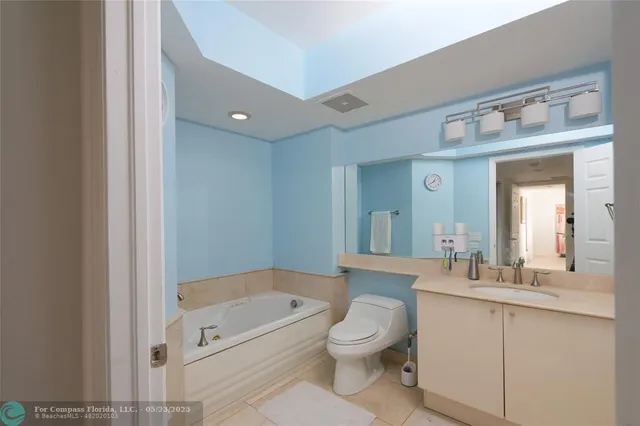a bathroom with a toilet a sink a mirror a bathtub and vanity
