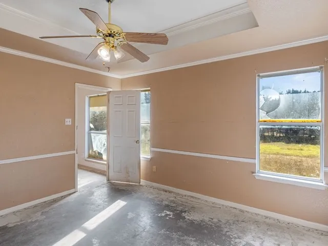 an empty room with windows and fan