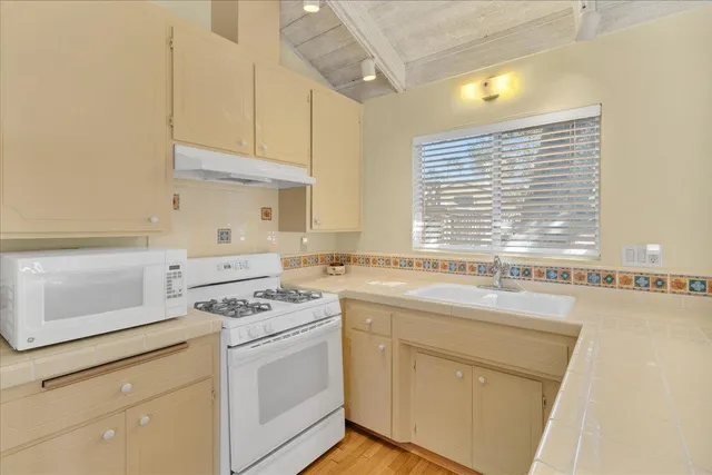 a kitchen with a sink a stove a refrigerator and white cabinets