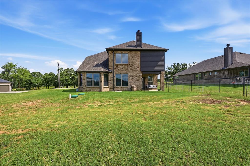864 Shadow Valley Road Whitesboro, TX 76273 - Photo 4 of 40 Expansive rear yard featuring a brick and siding exterior, multiple large windows, and a covered patio area