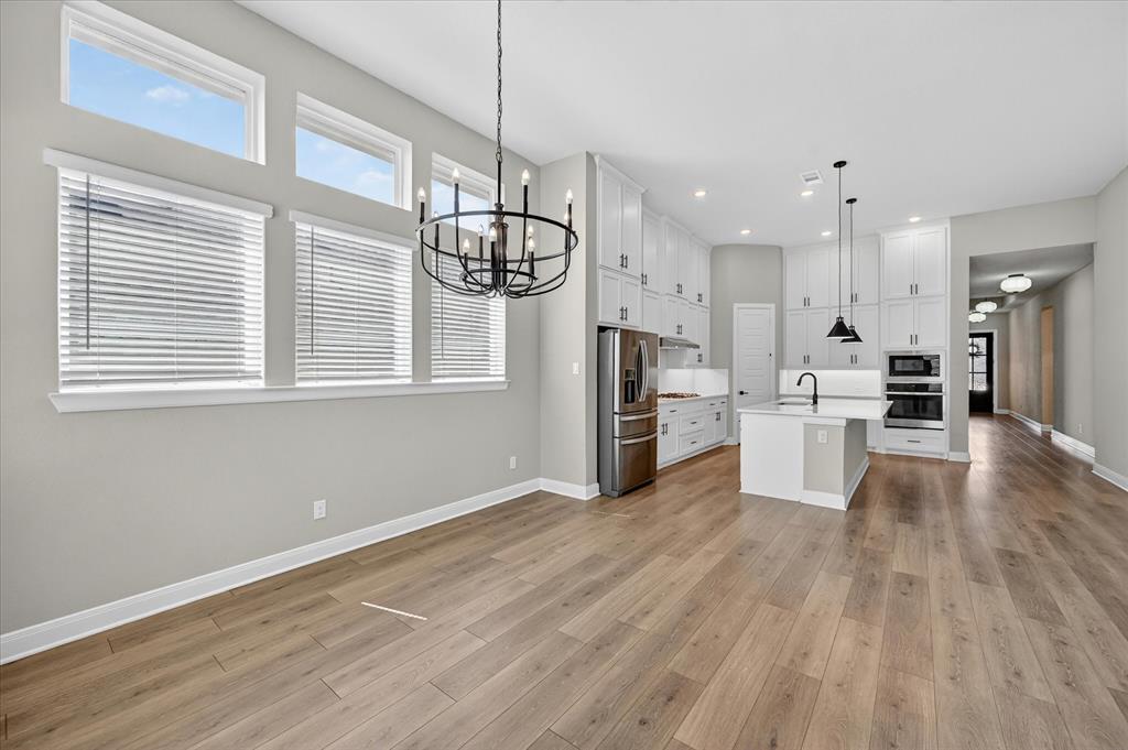 2237 Pika Road Northlake, TX 76247 - Photo 5 of 37 Open-concept interior featuring light wood-finish flooring, a contemporary black chandelier, and multiple windows