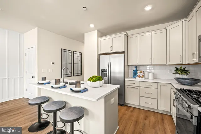 a kitchen with stainless steel appliances a white table chairs and a refrigerator