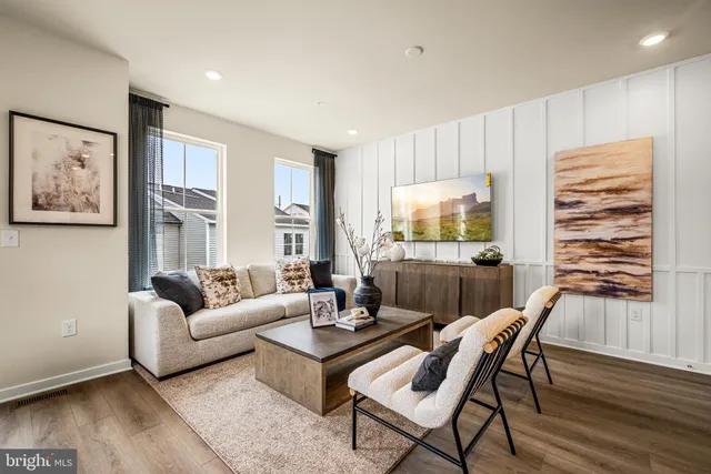 a living room with furniture a flat screen tv and wooden floor