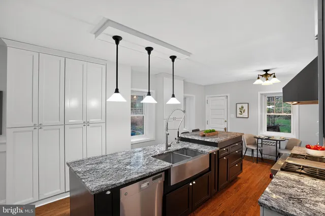 a kitchen with stainless steel appliances granite countertop a sink a stove and a wooden floors