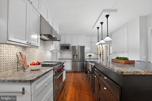 a kitchen with granite countertop a stove a sink a dining table and chairs