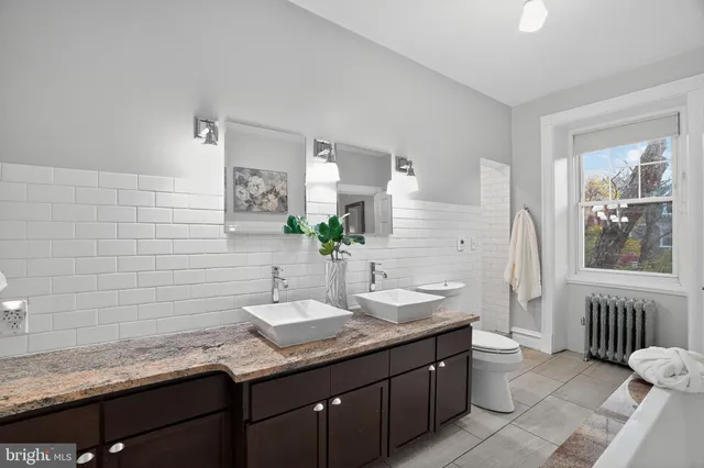 a bathroom with a granite countertop sink toilet and mirror