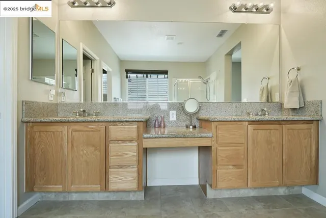 a bathroom with a granite countertop double vanity sink and a mirror