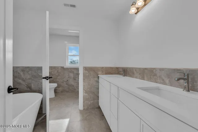 a view of empty room with wooden floor and kitchen